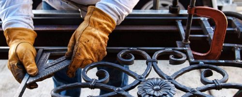 artisan fabriquant un portail en fer forgé sur mesure dans son atelier